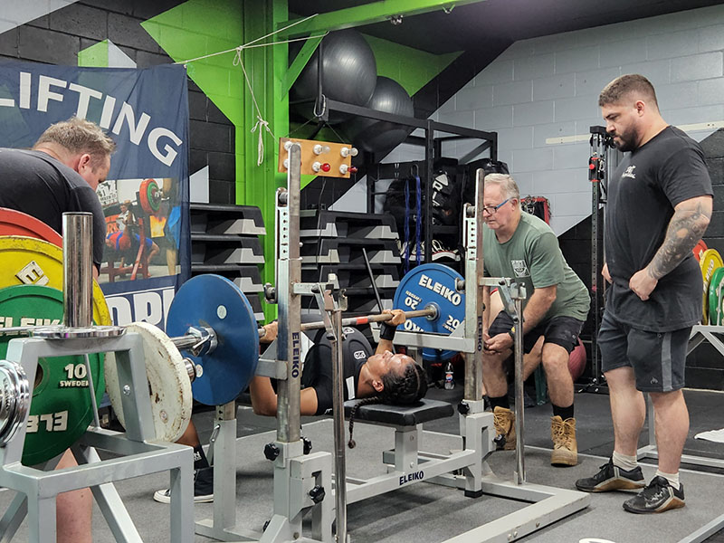 Man performing a bench press at a powerlifting event in Darwin.